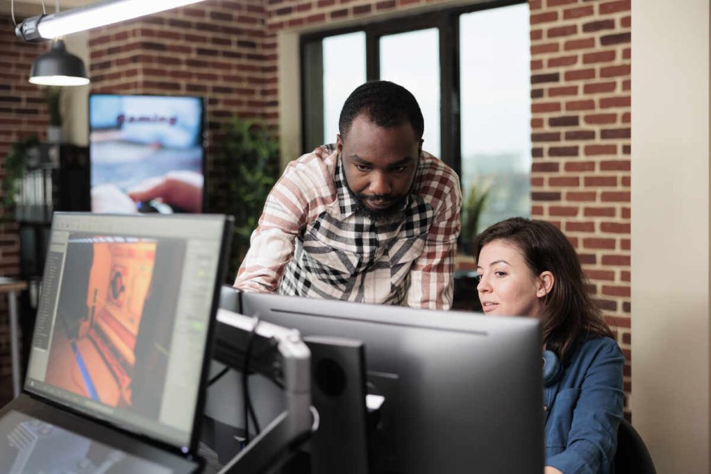 Creative company digital designer signaling faulty graphic software while in office workspace. Confident man pointing out mistakes in design blueprint while having conversation with colleague