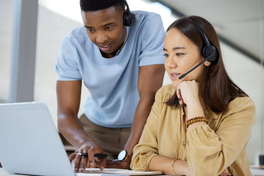 Shot of two businesspeople working together on a laptop in a call centre.