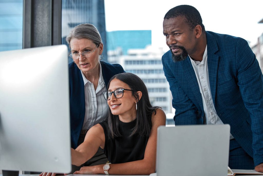 Shot of a diverse group of businesspeople having a discussion while using a computer in the office.