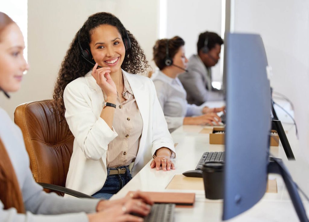 Portrait of a young call centre agent working alongside her colleagues in an office.